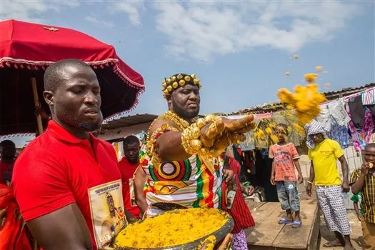 Culture & Heritage - Traditional Ghanaian chief in gold regalia at a cultural festival, leading a procession with attendants in Kumasi, Ghana.