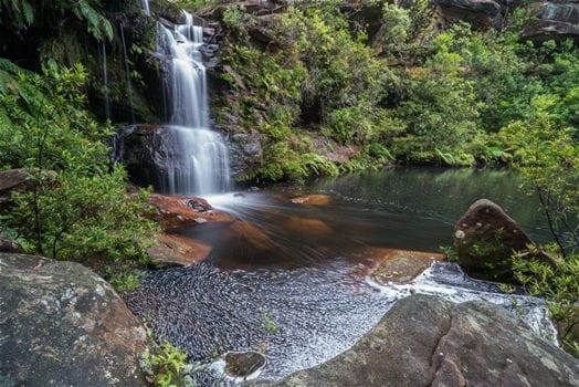 Place to See - Akaa Falls in Ghana, a breathtaking waterfall surrounded by greenery.