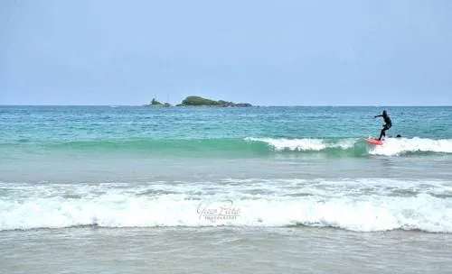 Place to See - Shortly before sunset over the serene waters of Busua Beach, Ghana, with a surfer riding the gentle waves.