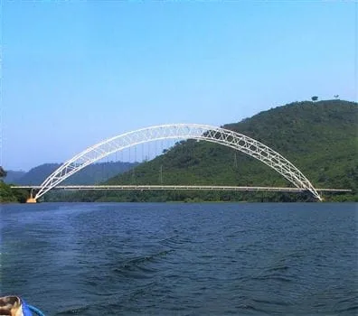 Destinations - The Adomi Bridge arching over the Volta River with green hills in the distance.