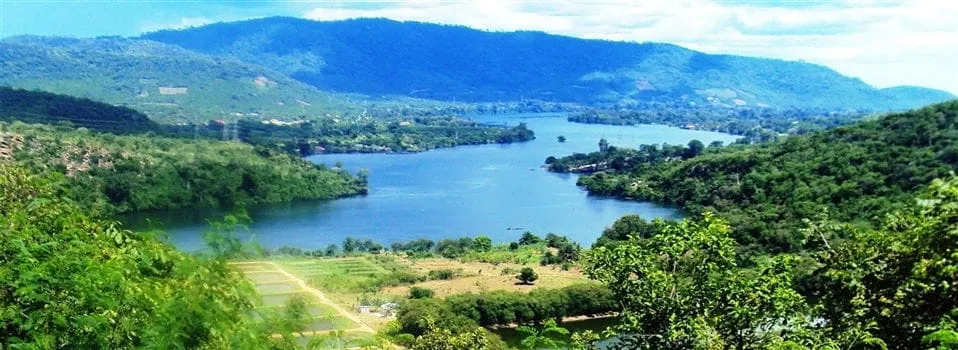  - A scenic view of Lake Volta surrounded by lush green hills and mountains under a bright blue sky.